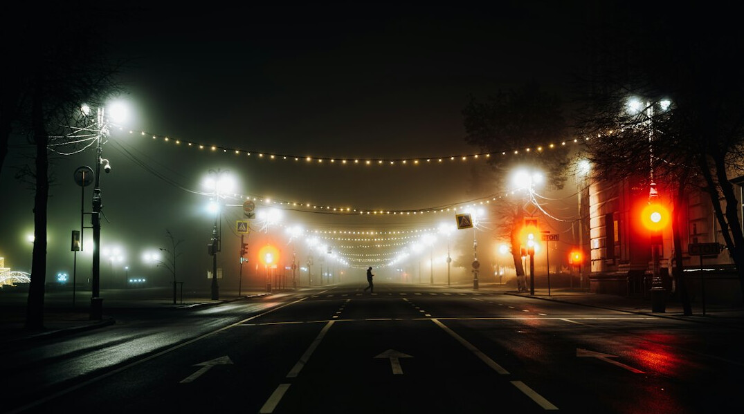Empty city street at dusk with lights and fog